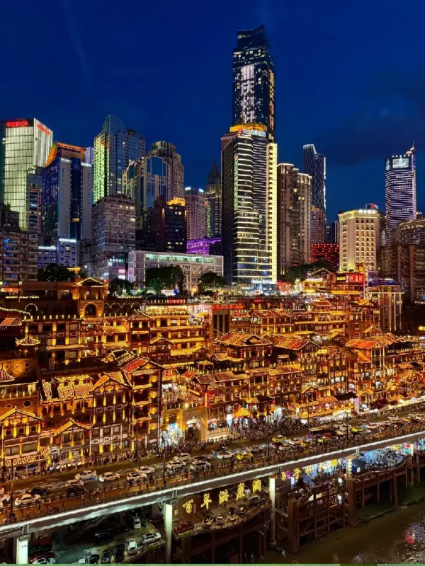 Chongqing 8D city night view featuring glowing traditional Hongyadong stilt-house complex next to modern Jiefangbei Pedestrian Street skyscrapers overlooking the Jialing River with tour boats and the Qiansimen Bridge